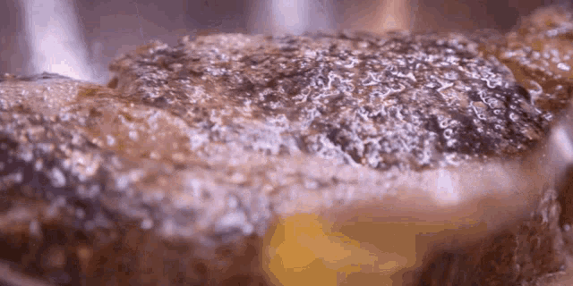 a close up of a piece of meat being cooked in a pan