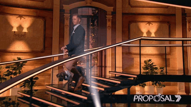 a man in a suit is walking down a set of stairs with a proposal 7 logo in the corner