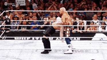 two wrestlers in a ring with a sign that says american nation on it