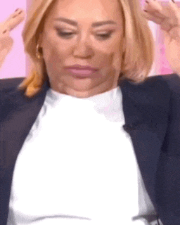 a woman in a suit is making a funny face with her hands .
