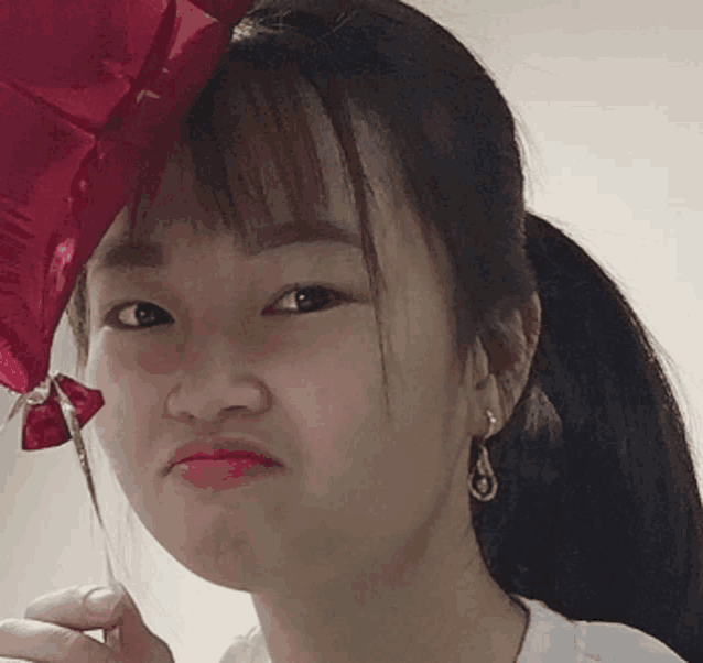 a woman is holding a red heart shaped balloon and making a funny face