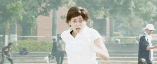 a woman in a white shirt is running in a park with people in the background .