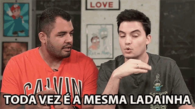 two men are sitting next to each other and one of them is wearing an orange calvin klein shirt