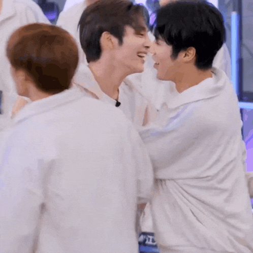 a group of young men are standing next to each other and hugging .