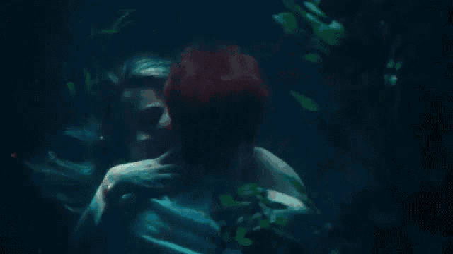 a man and a woman are kissing underwater in the dark .