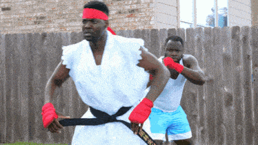 a man in a karate costume is standing next to another man in blue shorts