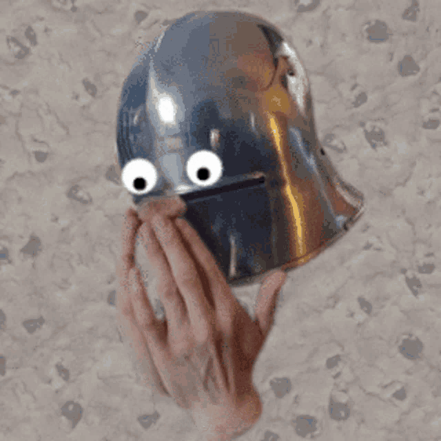 a person is covering their mouth with a helmet with googly eyes