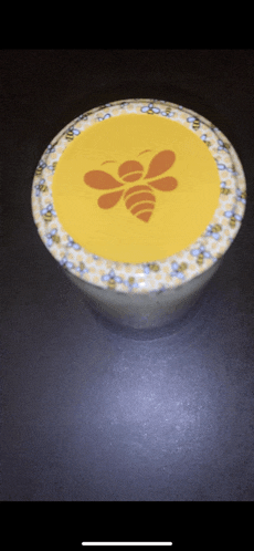 a jar with a bee on the lid is sitting on a table