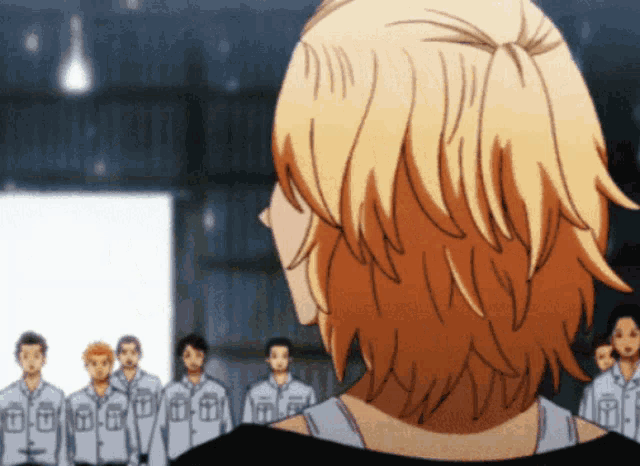 a man in a black shirt stands in front of a group of men in white shirts with the letter t on them