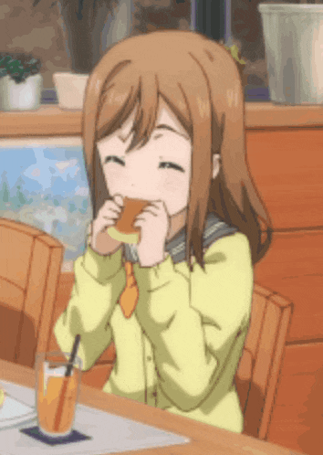a girl is sitting at a table with a glass of orange juice and eating a sandwich