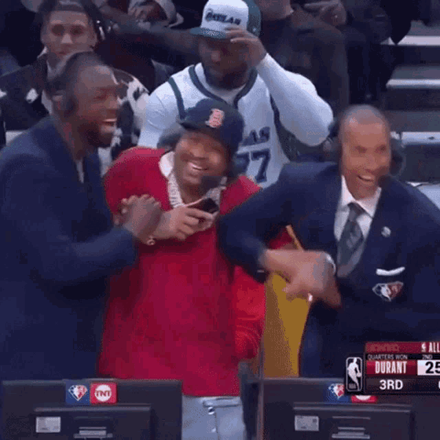 a man wearing a boston red sox hat is laughing while sitting in front of a tnt sign