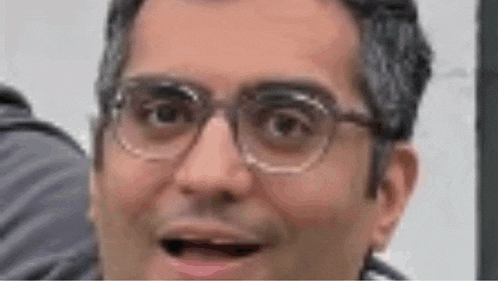 a man wearing glasses is making a surprised face .