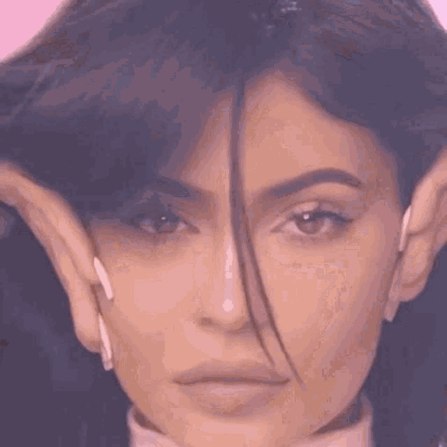 a close up of a woman 's face with her hands covering her ears .
