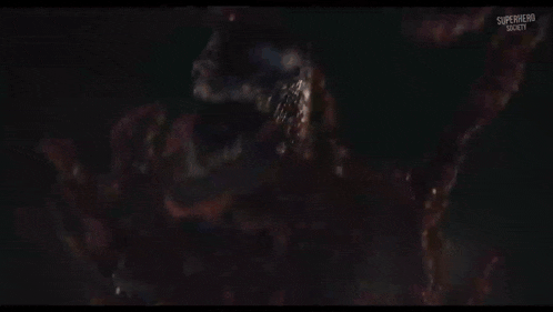 a close up of a person in a superhero costume holding a gun in a dark room .