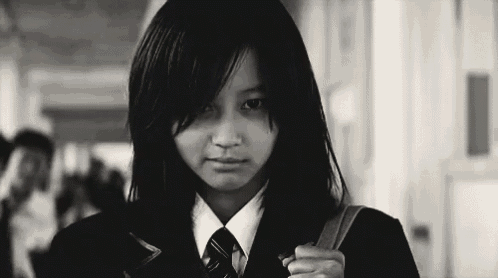 a young girl in a school uniform and tie is walking down a hallway .