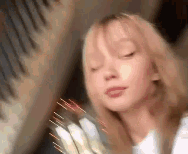 a close up of a woman 's face with her eyes closed holding a comb .