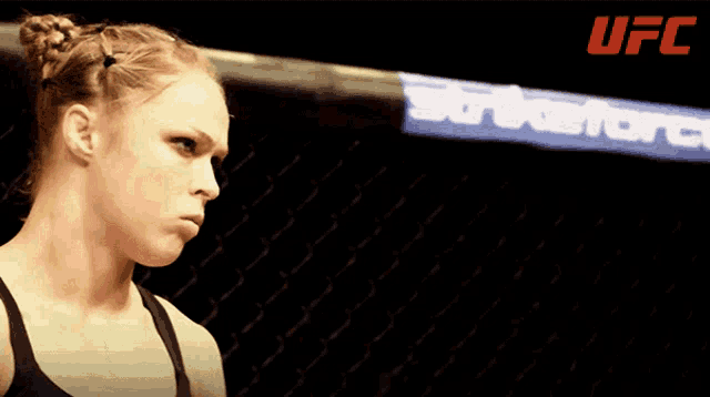 a woman stands in a boxing ring with a banner that says ufc on it