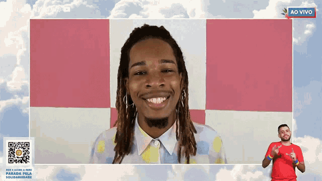 a man with dreadlocks is smiling in front of a pink and white checkered background with the words ao vivo in the corner