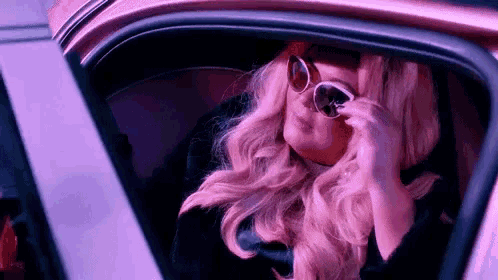 a woman wearing sunglasses is sitting in a car .