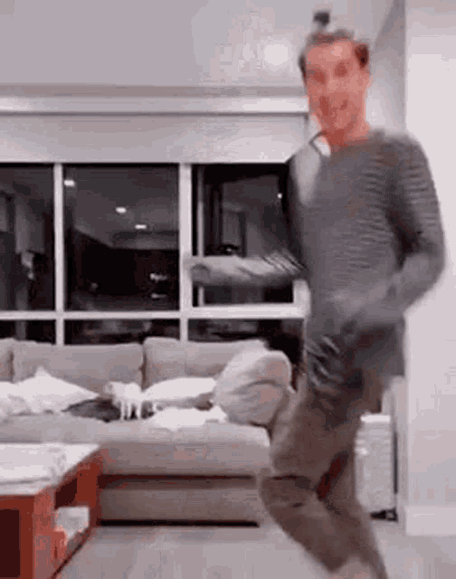 a man is dancing in a living room with a couch .