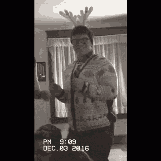 a black and white photo of a man wearing a reindeer antlers hat