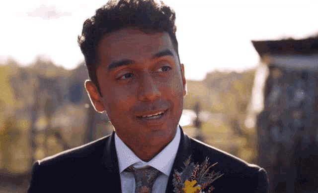 a man in a suit and tie with a flower in his lapel