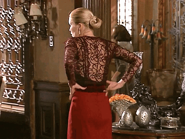 a woman in a red dress is standing in a room with a light switch on the wall