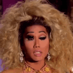 a close up of a woman 's face with a very large blonde wig .