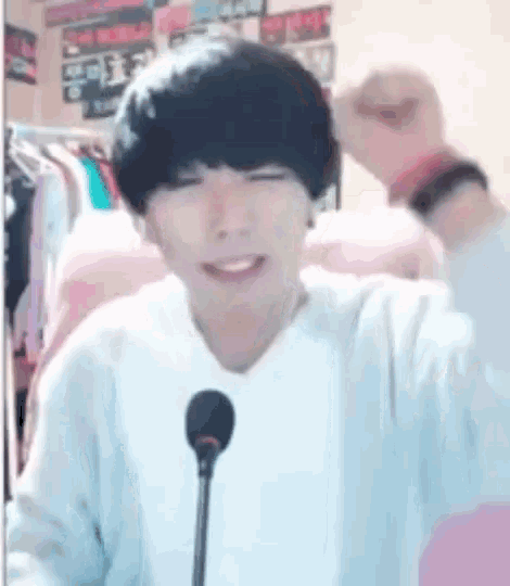 a young man is sitting in front of a microphone and making a funny face .