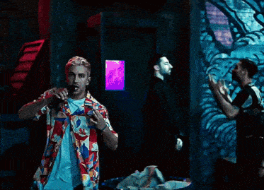 a man in a colorful shirt is singing into a microphone in front of a graffiti wall .