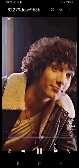 a man with curly hair is wearing a leather jacket .