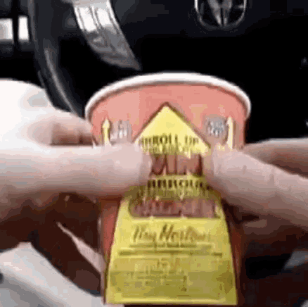 a person is holding a cup of tim hortons coffee