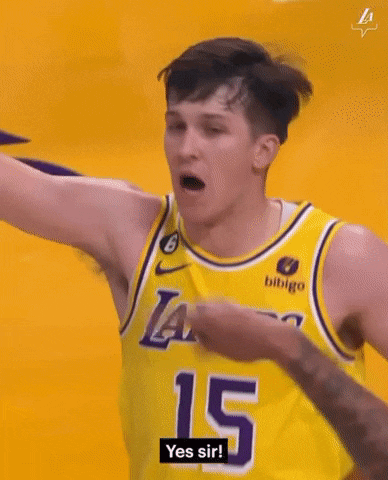 a basketball player wearing a yellow jersey is giving a fist bump to another player .