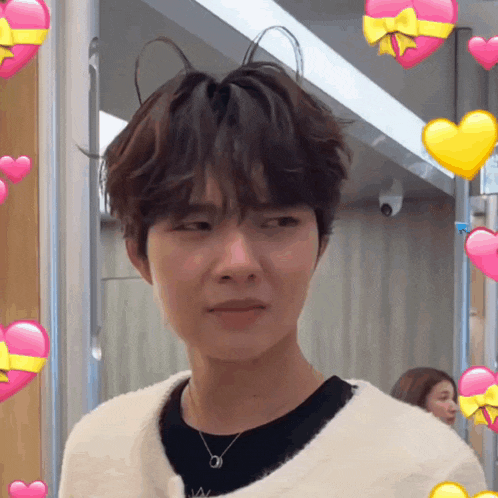 a young man with a necklace and hearts around him
