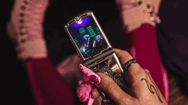 a person holding a flip phone with a green screen that says ' i 'm sorry ' on it