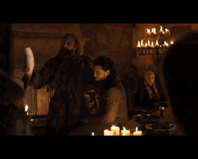 a man with a beard is holding a sword in a room with candles