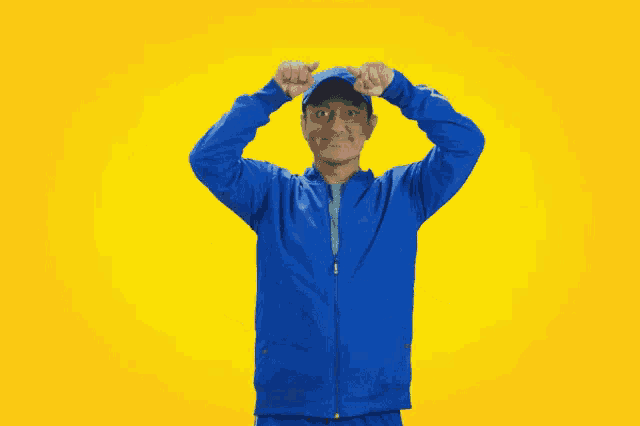 a man in a blue jacket and hat is making a face