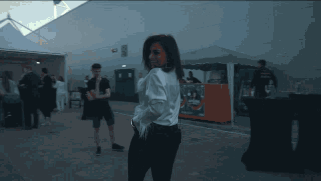 a woman in a white shirt stands in front of a sign that says ' a few steps ' on it
