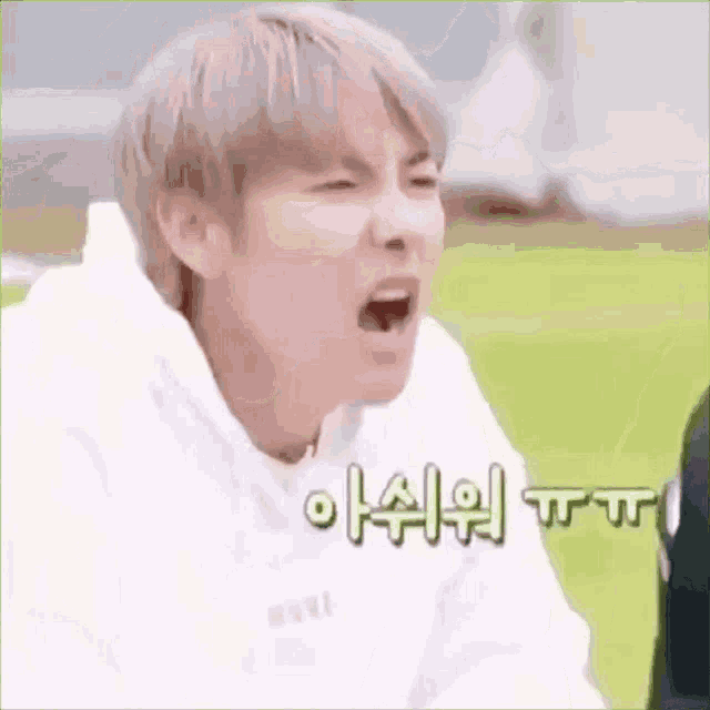a man in a white hoodie is making a funny face .