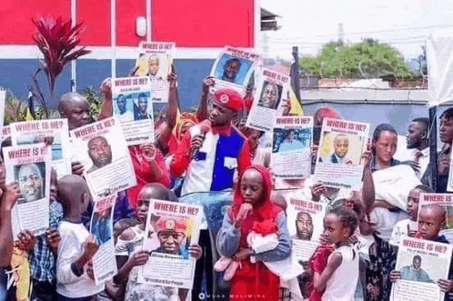 a group of people are holding up flyers asking where a man is .