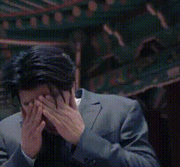 a man in a suit is holding his hands to his head .