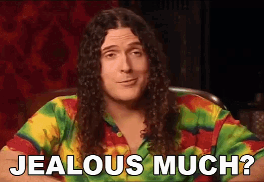 a man with long curly hair is wearing a tie dye shirt and saying jealous much