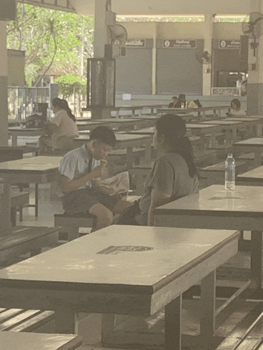 a boy sits at a table in a restaurant with a bottle of water on it