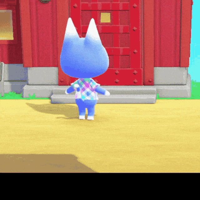 a blue cat with white ears is standing in front of a red building