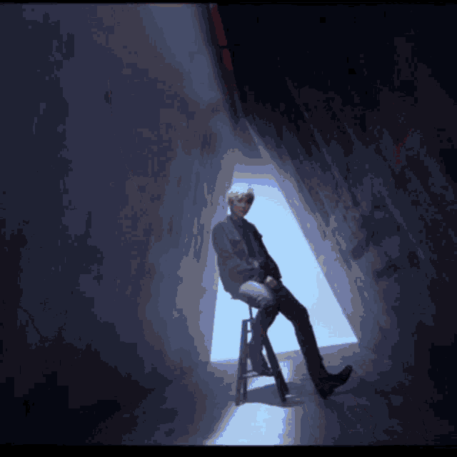 a person sitting on a stool in a dark room