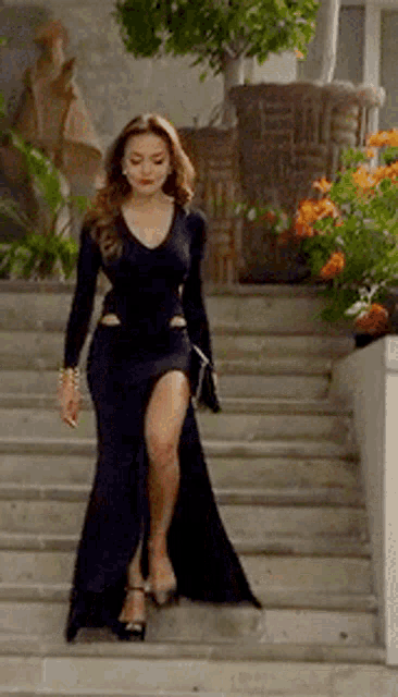 a woman in a black dress is walking down some stairs