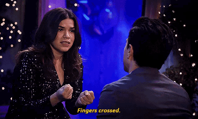 a man and a woman are sitting next to each other and the woman is saying fingers crossed