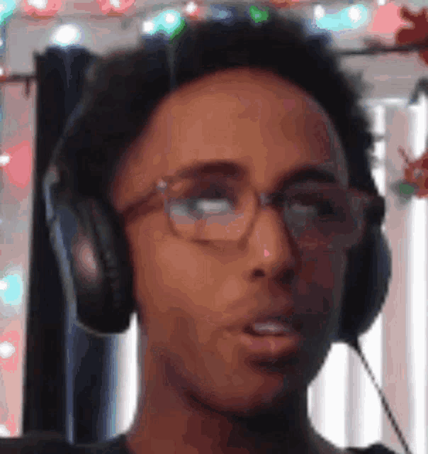 a young man wearing headphones and glasses looks at the camera