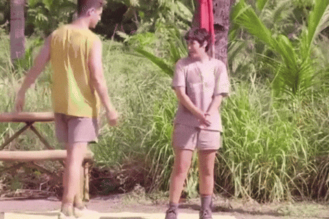 a man and a woman are standing next to each other in front of a picnic table in the jungle .
