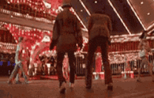 a couple of people walking in a casino holding hands .